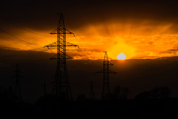 Fototapeta premium High voltage power line at sunset. Silhouettes of the metal pillars