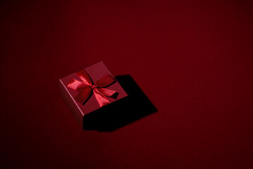 Red gift box with a bow on a red background with space for text. Gift on a red background. The perfect concept for holiday