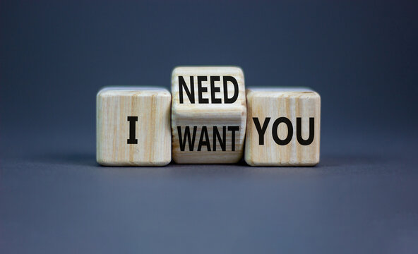 I need and want you symbol. Psychologist turns wooden cubes and changes words I want you to I need you. Beautiful grey table grey background, copy space. Psychological i need and want you concept.