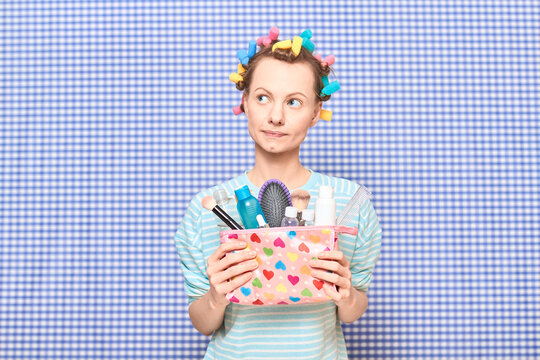 Dreamy Young Woman With Colorful Hair Curlers Is Holding Makeup Bag