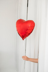 Red balloon in the shape of a heart on a white background. Happy Valentine's Day