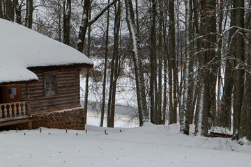 snow covered old brown wooden house in the winter field