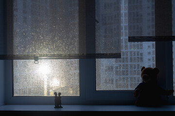 Dark silhouette of a window on a rainy morning or evening with water drops on the glass