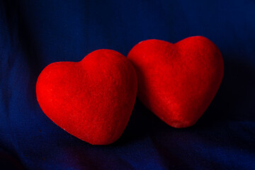 Fototapeta premium Two red corduroy hearts on a dark blue background. The concept of love, relationship, engagement, wedding.