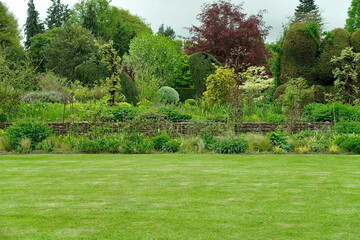 Scenic view of a beautiful English style landscape garden with a green mowed lawn and colourful flower bed