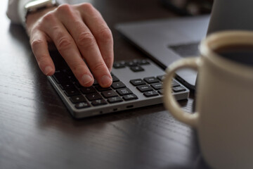 Using a peripheral numeric keypad next to laptop on desk.