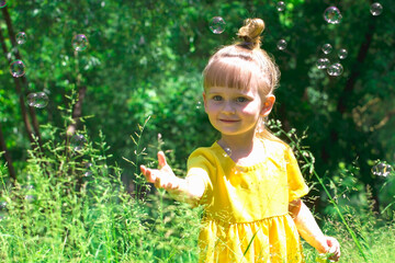 Little girl blows soap bubbles - obrazy, fototapety, plakaty