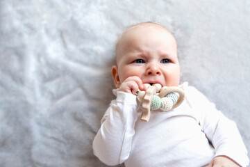Baby is craying and biting teething ring toy - obrazy, fototapety, plakaty