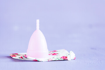 Menstrual cup with cotton pocket on violet background