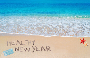 healthy new year written on the sand