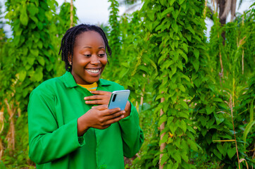 excited beautiful african female farmer using her phone