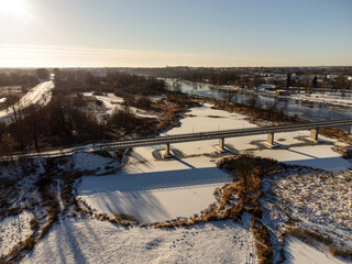 City, river and bridge on a sunny winter snowy day seen and photographed from a height.