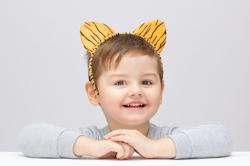 lovely adorable kid with a tiger or lion ears on grey background