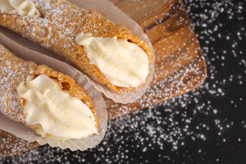 Top view of two delicious cannoli on black background