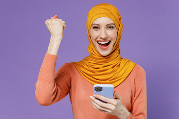 Smiling overjoyed young arabian asian muslim woman in abaya hijab yellow clothes hold in hand use...