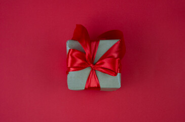 Gift box with red bow on red background. Festive background. Copy space.