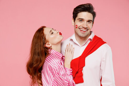 Young smiling happy fun couple two friends woman man with lipstick lips on face wear casual shirt hug cuddle isolated on plain pastel pink background. Valentine's Day birthday holiday party concept.