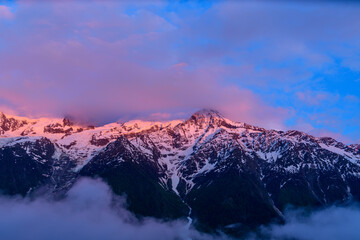 Naklejka na ściany i meble The Mont Blanc Massif surrounded by pinkish clouds in Europe, France, the Alps, towards Chamonix, in summer.