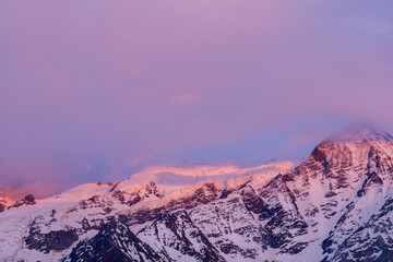 Mont Blanc surrounded by pink clouds at sunset in Europe, France, the Alps, towards Chamonix, in summer.