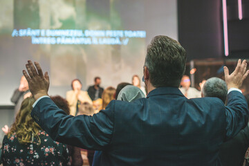 Hands in the air of people who praise God at church service - obrazy, fototapety, plakaty