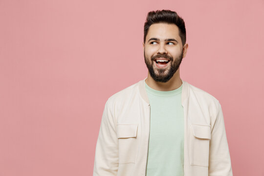 Young smiling cheerful happy caucasian man 20s wearing trendy jacket shirt look aside on workspace area mock up isolated on plain pastel light pink background studio portrait People lifestyle concept