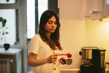 Young woman making morning coffee in the kitchen.