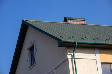 The roof of the house is made of red metal tiles, a beautiful large chimney