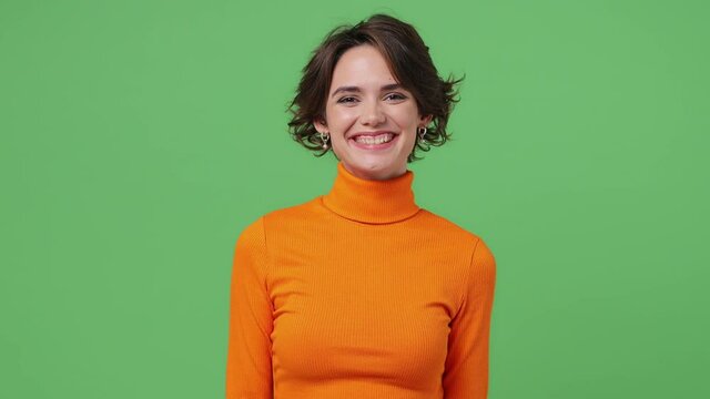 Smiling cheerful fascinating fun young brunette woman 20s wears orange shirt showing okay ok zero fingers gesture isolated on plain green background studio portrait. People emotions lifestyle concept