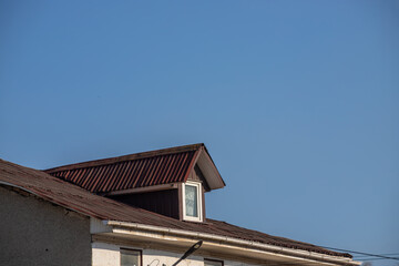 The roof of the house is made of red metal tiles, a beautiful large chimney