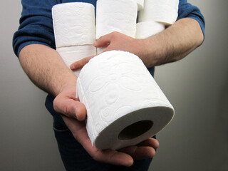    People are preparing toilet paper for home quarantine from Coronavirus. Man holds many rolls of toilet paper    