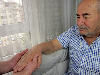    The hands of the young person holding the hand of an old person to kiss. Parent, respect.. 