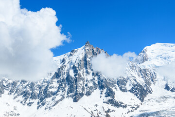 Obraz premium Clouds frame the Aiguille du Midi in the Mont Blanc massif in Europe, France, the Alps, towards Chamonix, in summer, on a sunny day.