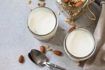 Obraz na płótnie Canvas Healthy breakfast, yogurt parfait. Yogurt with homemade almond granola on a gray concrete background. Top view flat lay. Copy space.