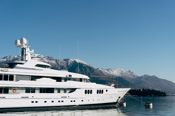 Fototapeta na wymiar White two-deck yacht moored at the pier with mountains in the background