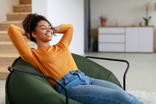 Calm black woman having rest at home on the puff