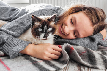 Teenage girl plays with a cat at home