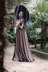 Naklejka premium Beautiful blonde girl in a trendy evening dress among tropical plants. Fashion and beauty, style.