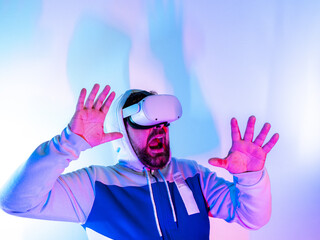 Young man wearing virtual reality headset playing in the metaverse - scared player with both hands in the air - VR goggles