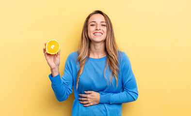 pretty woman laughing out loud at some hilarious joke holding half orange