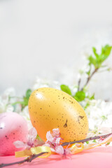 Happy Easter Spring Holiday Greeting Card Background with Easter colorful eggs, decorative bird nests and blossom spring garden flowers, flatlay copy space on high-colored pink background