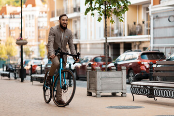 A businessman with a beard and in a suit rides a bicycle to work. Eco-friendly mode of transport,...