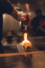 Persona con soplete caramelizando un trozo de pescado