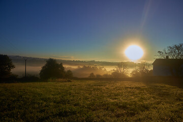 Naklejka na ściany i meble Sunrise in a rural area with fog
