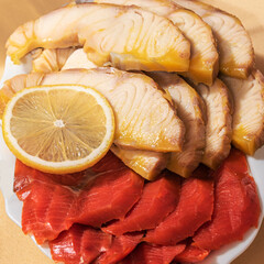 Sliced gourmet fish sturgeon and wild salmon on a plate on the festive table.