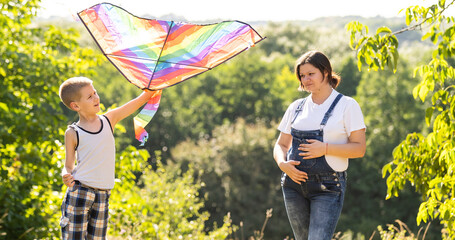 pregnant woman with her son playing a kite