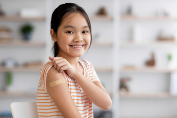 Healthy asian girl got vaccinated, showing band and smiling