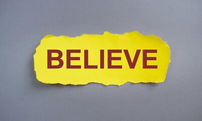 The word Believe concept and theme written on piece yellow tear paper