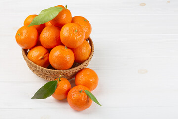 Fresh clementine mandarins or tangerines in a wooden bowl on white background with copy space