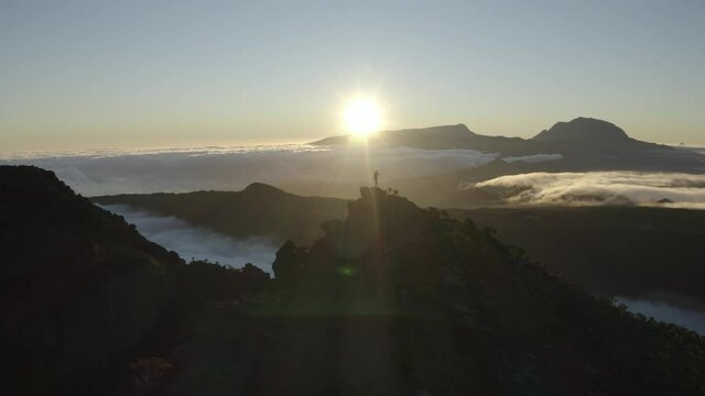 Aerial view of a person standing on the mountain top at sunset near Trou Fanfaron and Commerson Crater, Saint Joseph, Reunion.