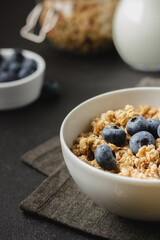 Granola with blueberry in bowl on dark napkin.